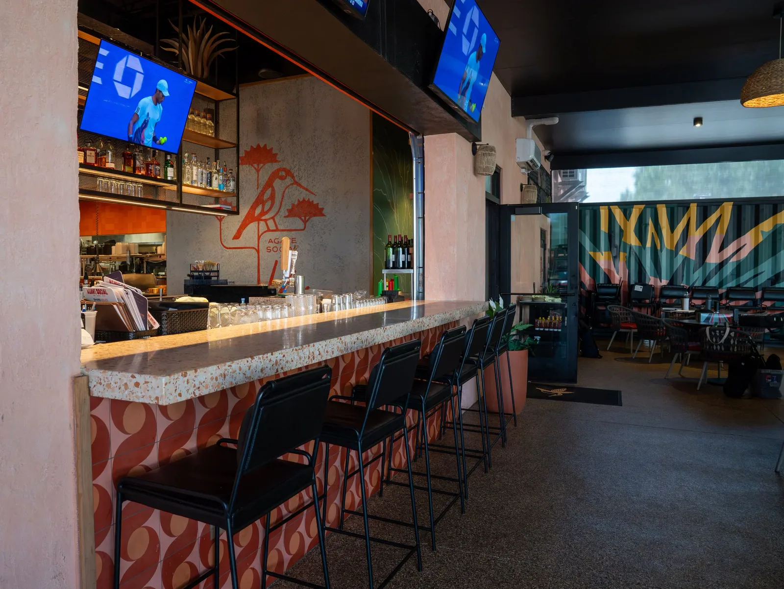 The terrazzo bar with blush tile front, screens and the hummingbird mural