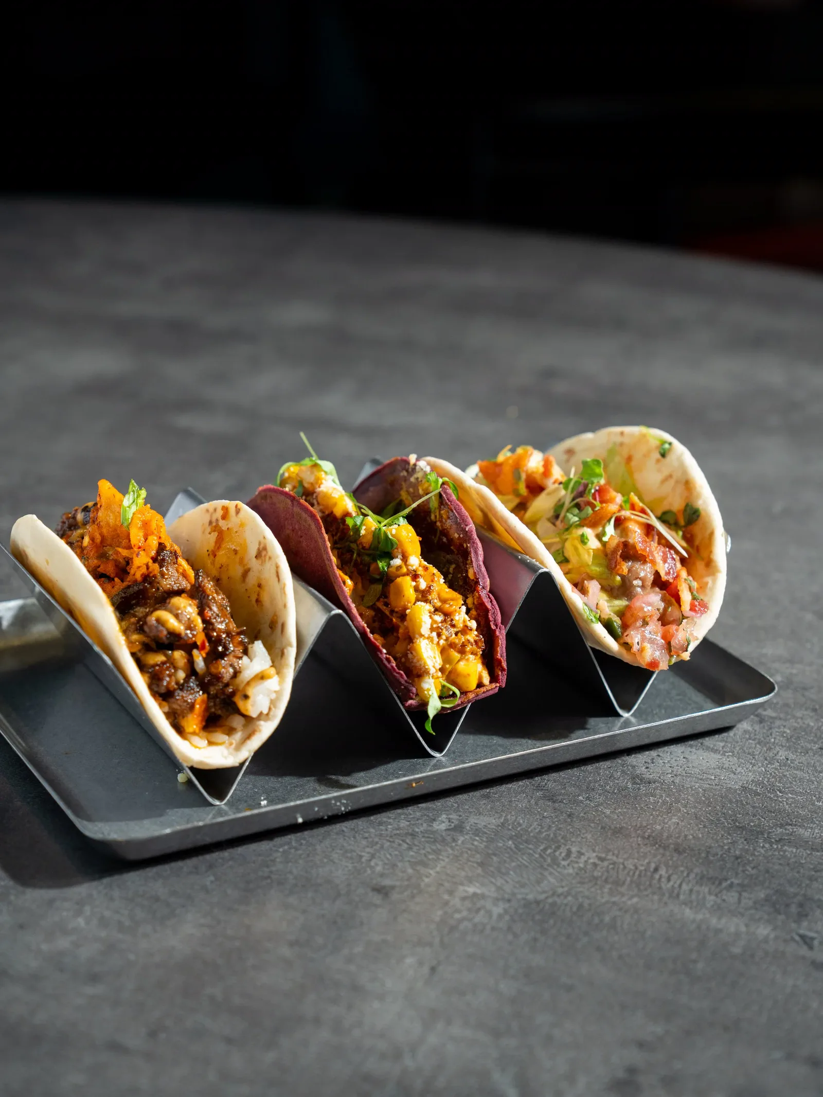 Three tacos in a metal taco holder